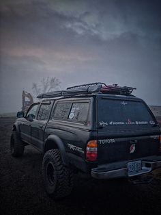 an off road vehicle parked in the middle of a field with dark clouds behind it