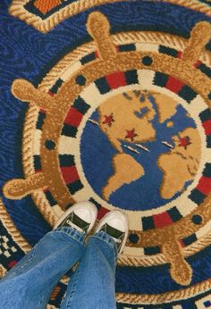 a person standing in front of a rug with a world map on it's center