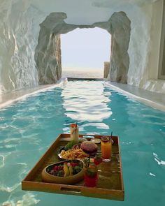 an indoor swimming pool with food and drinks on the trays in front of it