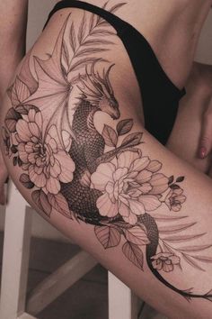 a woman's thigh with flowers and a koi fish tattoo on her leg