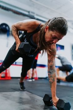 a woman doing push ups with dumbbells in a crossfit gym area