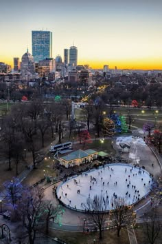 an aerial view of a skating rink in the middle of a city at dusk with people skating on it