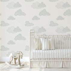 a baby's room with a crib, rocking horse and clouds wallpaper