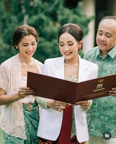 two women and a man are looking at a book