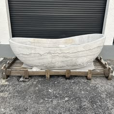 a large white boat sitting on top of a wooden pallet next to a garage door