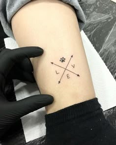 a person with a tattoo on their arm holding a dog's paw and an arrow