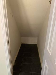 an empty room with black tile flooring and white trim on the door way to another room