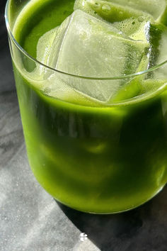 a glass filled with green liquid on top of a table