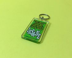 a green keychain with the word fresh on it sitting on a yellow surface