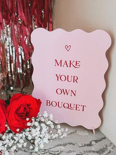 a pink sign that says make your own bouquet next to some red roses and streamers