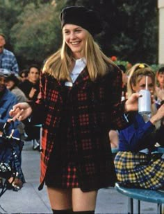 a young woman is walking down the street with her hands in her pockets and smiling