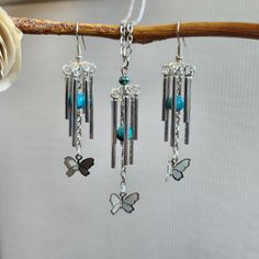 three wind chimes hanging from a tree branch with butterfly charms attached to the strings