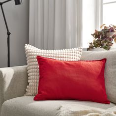 a red pillow sitting on top of a white couch