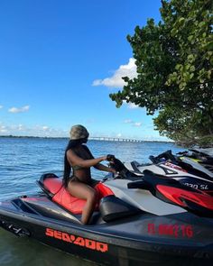 a woman riding on the back of a black and red jet ski in the water