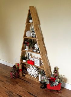 a christmas tree made out of wooden shelves with ornaments on top and decorations below it