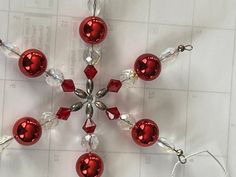 a snowflake made out of red and clear glass beads on a white background