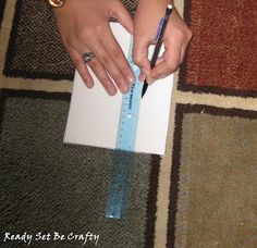 a person is holding a pencil and writing on a piece of paper with a ruler