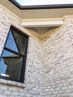 a cat sitting on the ledge of a brick building next to a window with a skylight above it