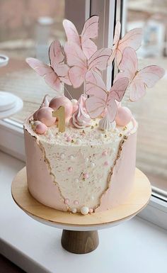 there is a cake with pink butterflies on it sitting on a window sill next to the windowsill