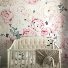 a white crib in front of a floral wallpapered nursery with pink roses