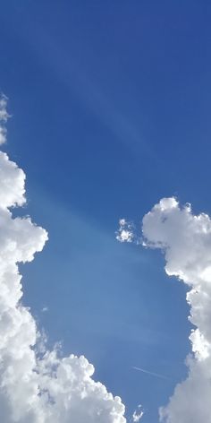 an airplane is flying through the blue sky with white clouds in the foreground,