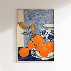 an oranges are sitting on a plate in front of a blue and white vase