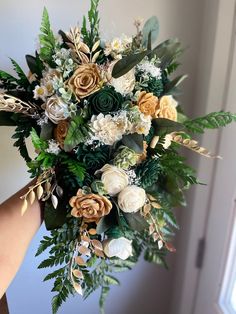 a woman holding a bouquet of flowers with greenery and foliage on the bottom half