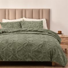 a bed with green comforter and pillows in a room