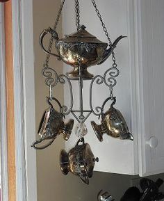 a metal teapot hanging from the side of a kitchen cabinet with pots and pans attached to it