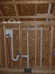 an unfinished room with exposed plumbing and wood framing on the walls, including pipes and piping