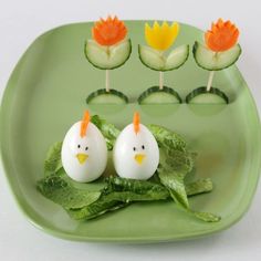 two eggs in the shape of chickens sitting on top of lettuce and cucumber slices