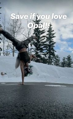 a woman doing a handstand on the side of a road with trees in the background