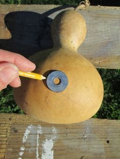 a person holding a pencil in front of a wooden object with a face on it