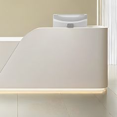 a white reception desk with an electronic device on it's back end, in front of a beige wall