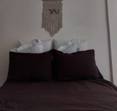 a bed with two pillows and a decorative wall hanging above it