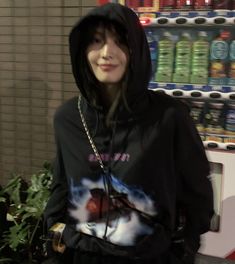 a woman wearing a hoodie standing in front of a vending machine