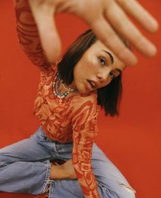 a woman sitting on the ground with her hand up