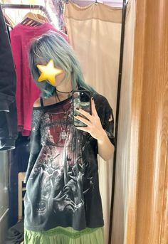 a woman with blue hair taking a selfie in front of a mirror wearing a star