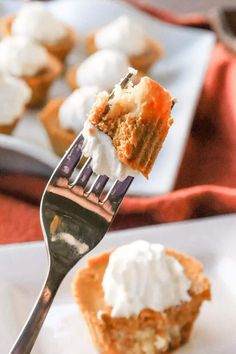 a fork is holding up a piece of carrot cupcake with whipped cream on top