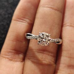 a close up of a person's hand holding an engagement ring