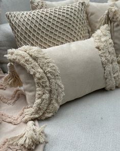 pillows with tassels and fringe on them are sitting on a couch in the living room