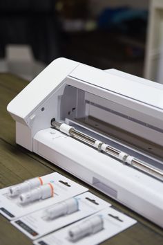 a machine that is sitting on a table next to some papers and pens in front of it