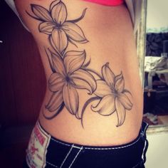 a woman's lower back tattoo with flowers on her stomach and the bottom half