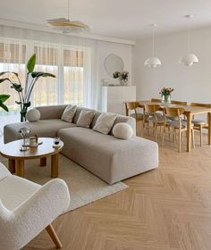 a living room filled with furniture next to a wooden table and white curtains on the windows