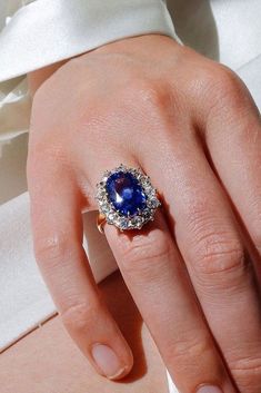 a close up of a person's hand wearing a ring with a blue stone