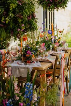 an outdoor table set with flowers and candles