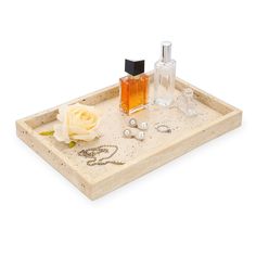 a white rose sitting on top of a tray with jewelry and perfume bottles in it