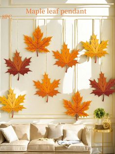 a living room filled with furniture and lots of fall leaves hanging on the wall above it