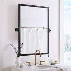 a bathroom with a sink, mirror and towels hanging on the rack in front of it