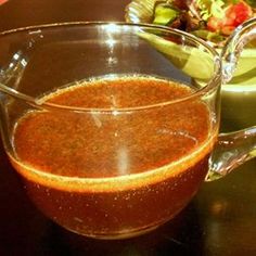 a glass pitcher filled with liquid sitting on top of a table next to a bowl of salad